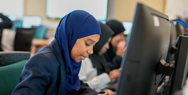 A pupil works at a desktop computer in the ICT suite.
