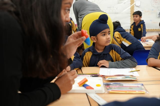 Pupils discuss a practical classroom activity with their teacher.