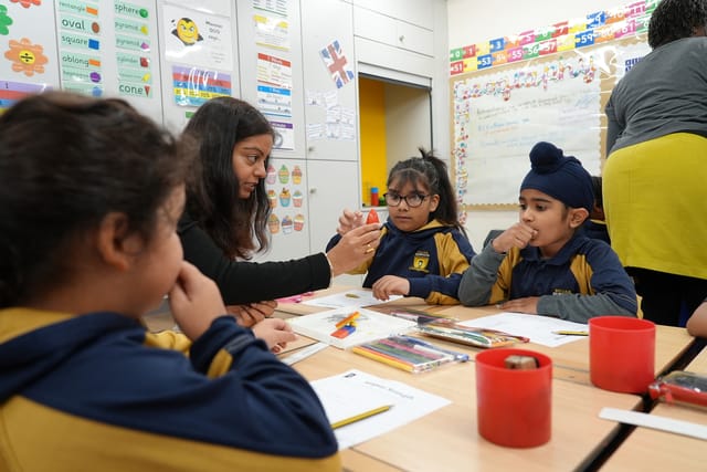 A teacher helps pupils with a hands-on classroom activity.