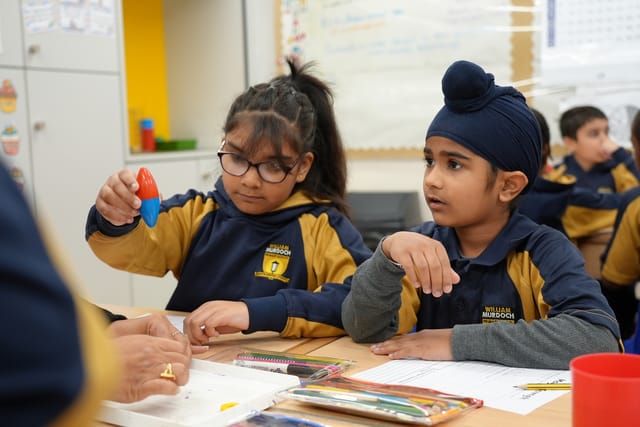 Pupils handle small learning materials during a classroom activity.