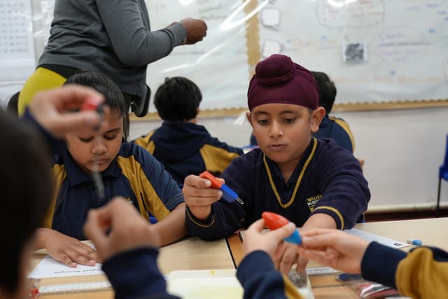 Pupils take part in a hands-on classroom activity using small materials.