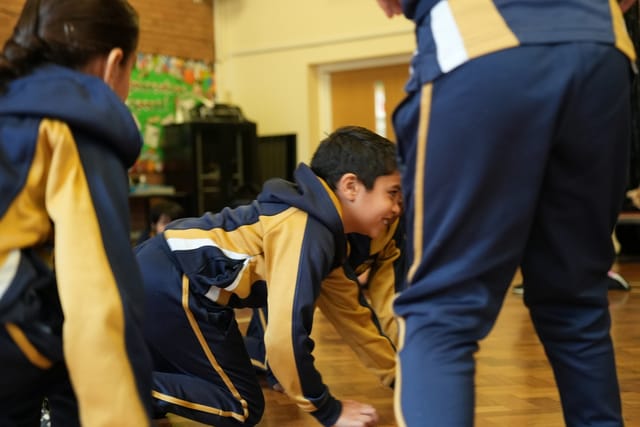 Pupils move across the school hall floor during a PE activity.