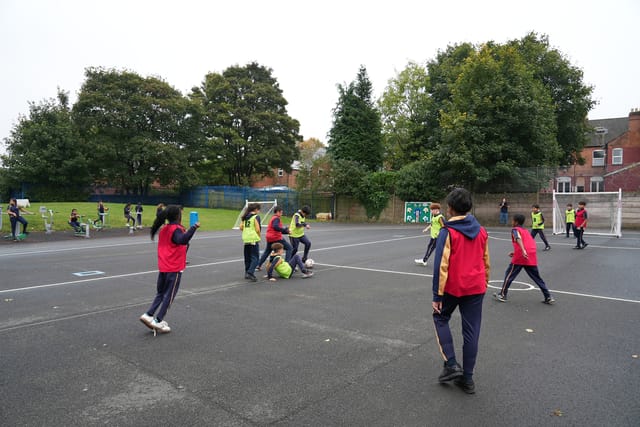 Pupils play team football on the school playground.