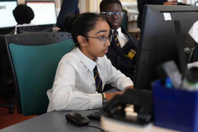 A pupil works at a desktop computer in the ICT suite.
