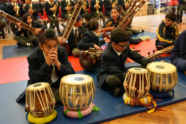 Pupils sit with tabla drums during a music lesson.