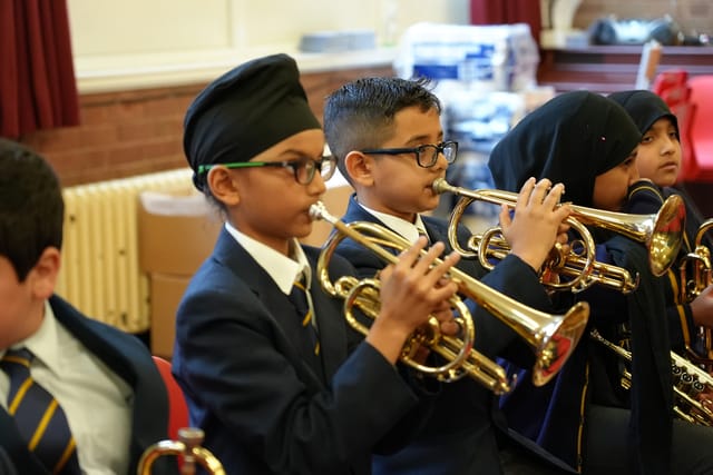 Pupils in school uniform play brass instruments during a music lesson.