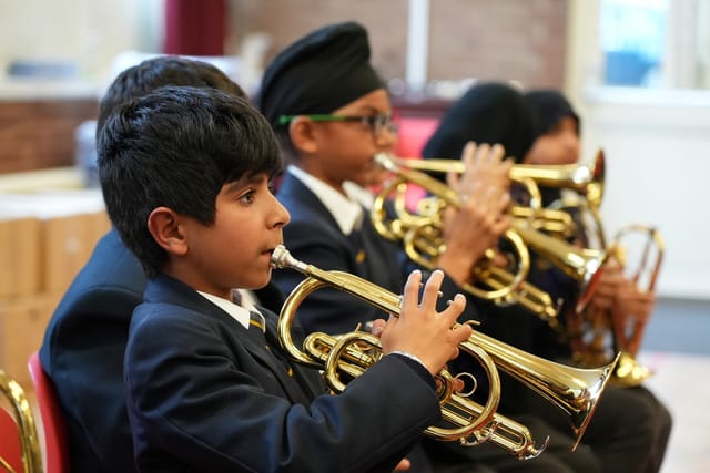 Pupils play brass instruments together during a music lesson.