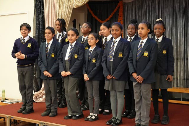 Pupils stand together on stage during a school performance or assembly.