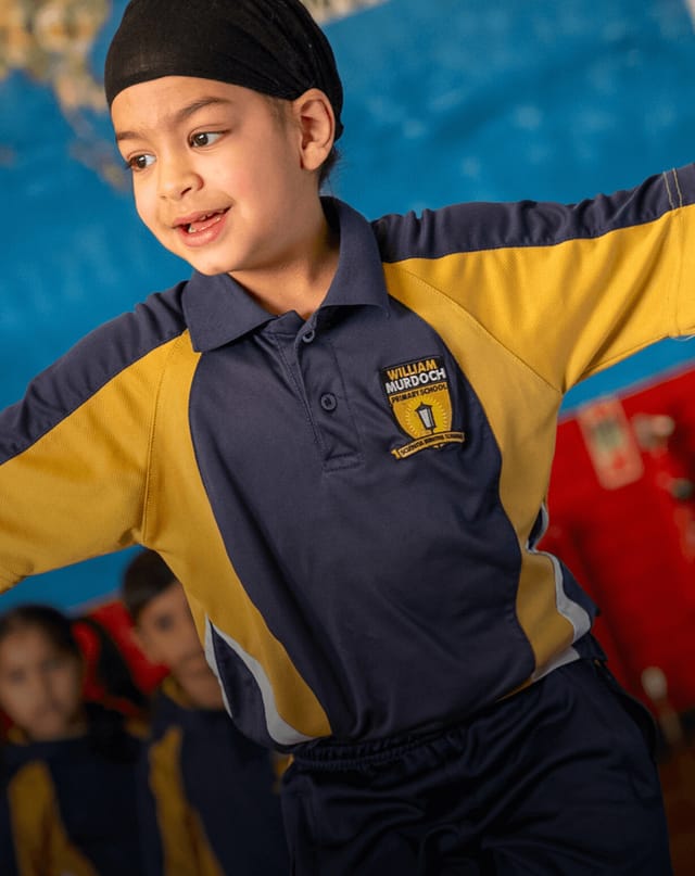 A pupil in school PE kit balances during an activity in the school hall.